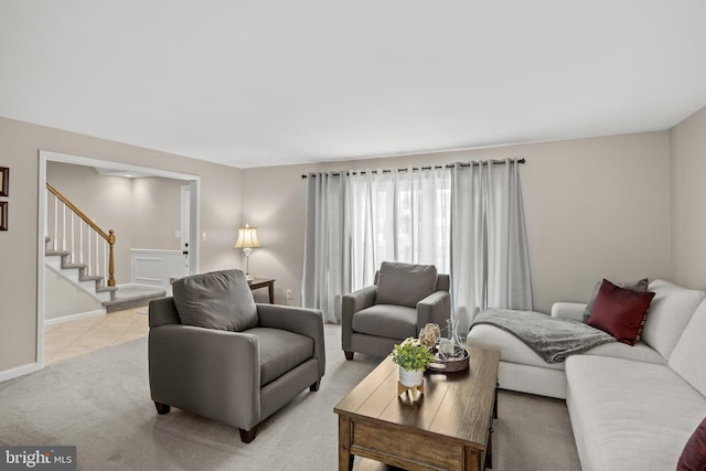 living area featuring stairway, light carpet, and baseboards