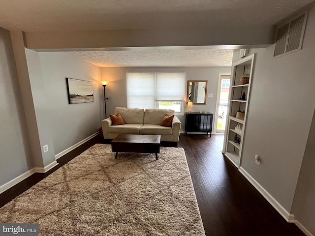 living room featuring dark wood-style floors, baseboards, a textured ceiling, and beam ceiling