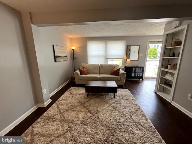 living area with dark wood finished floors, baseboards, and a textured ceiling