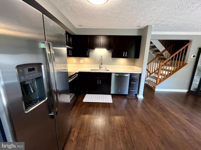 kitchen featuring appliances with stainless steel finishes, dark wood-type flooring, light countertops, a sink, and baseboards