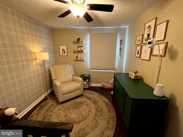 sitting room with ceiling fan, a textured ceiling, baseboards, and wood finished floors