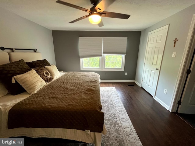 bedroom featuring dark wood finished floors, baseboards, and a ceiling fan