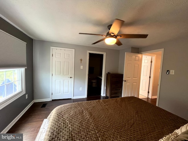 bedroom featuring dark wood finished floors, baseboards, ceiling fan, and a textured ceiling