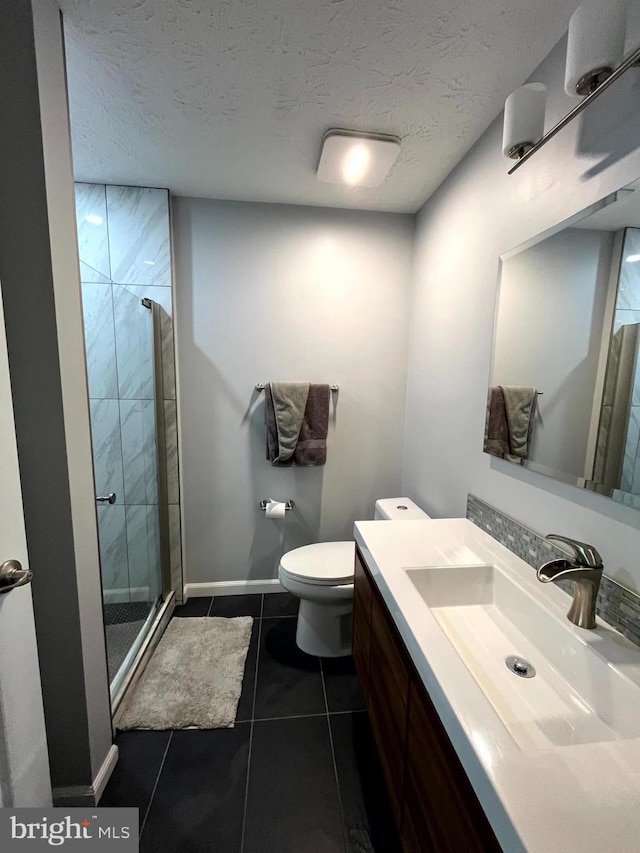 full bath with a stall shower, vanity, tile patterned flooring, toilet, and a textured ceiling