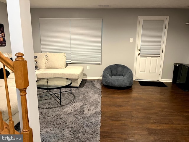 living room featuring wood finished floors, baseboards, and stairs