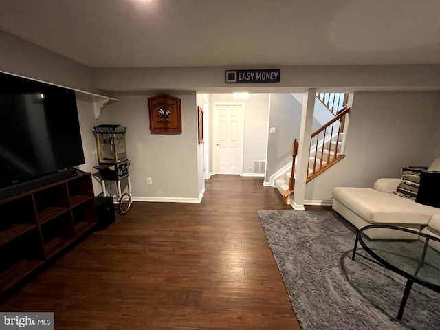 living area with baseboards, dark wood-style flooring, and stairs