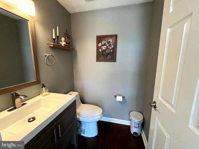bathroom with wood finished floors, baseboards, vanity, and toilet
