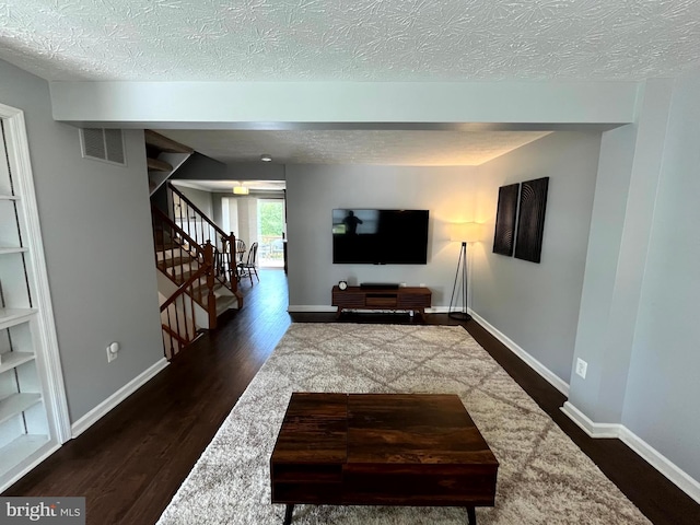living area featuring stairs, dark wood-style floors, a textured ceiling, and baseboards
