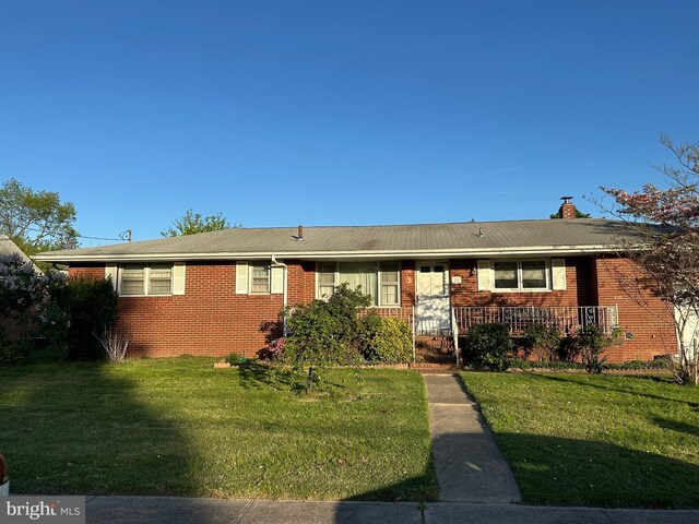 single story home with brick siding, a front yard, and a chimney