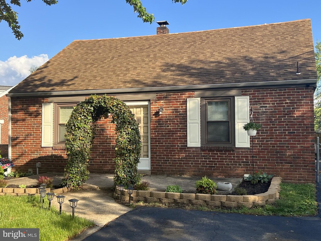 view of front of house featuring a shingled roof and brick siding