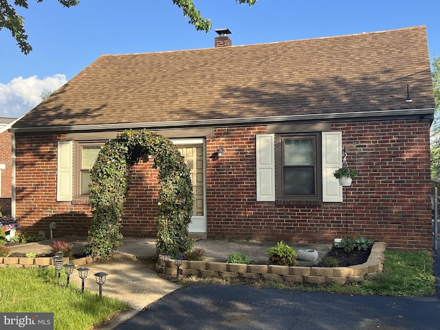 view of front of house featuring a shingled roof and brick siding