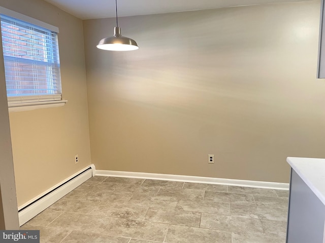 unfurnished room with a baseboard heating unit and baseboards