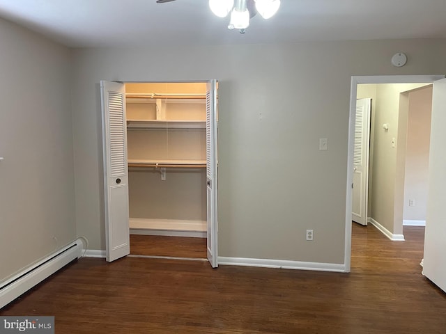 unfurnished bedroom with a baseboard heating unit, dark wood-style floors, a closet, and baseboards