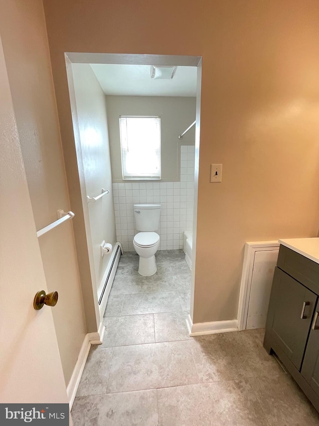 bathroom featuring baseboard heating, tile patterned floors, toilet, tile walls, and vanity