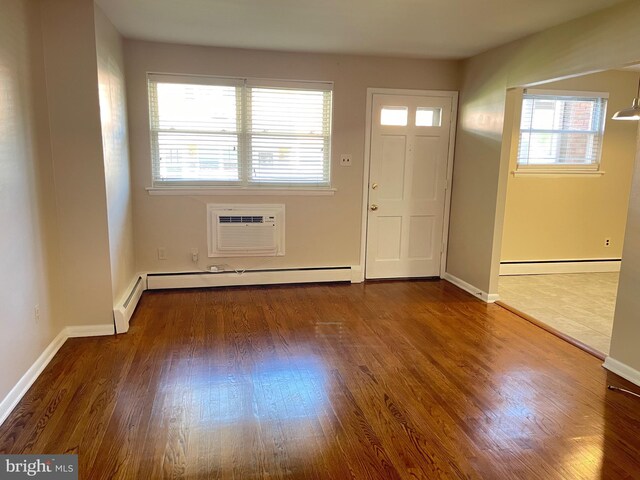 foyer with a wall mounted air conditioner, wood finished floors, a baseboard heating unit, and baseboards
