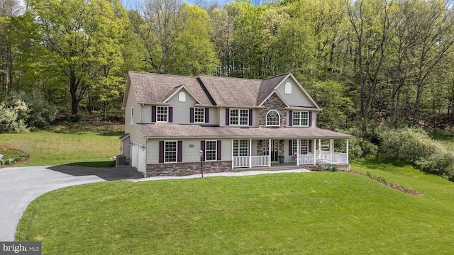 view of front of house featuring covered porch, driveway, stone siding, and a front lawn