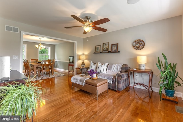 living room with light wood-style flooring, baseboards, ceiling fan, and a chandelier