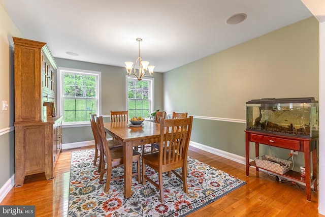 dining space with light wood-style flooring, baseboards, and a chandelier