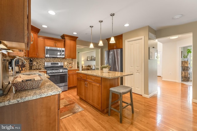 kitchen featuring appliances with stainless steel finishes, a sink, light stone counters, tasteful backsplash, and recessed lighting