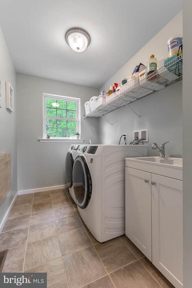 clothes washing area with washing machine and clothes dryer, light tile patterned floors, cabinet space, and baseboards