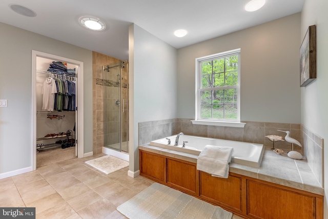 bathroom with a shower stall, a walk in closet, a garden tub, and tile patterned flooring