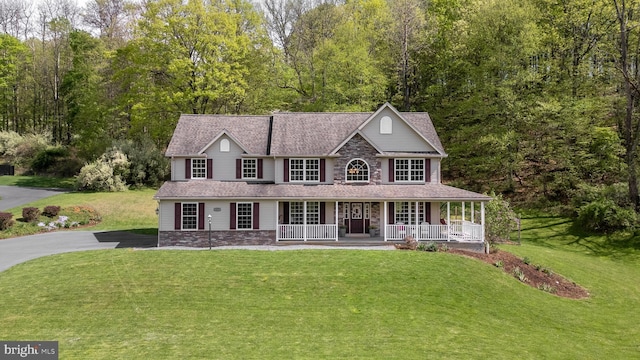 view of front of house featuring a porch, a front yard, stone siding, and asphalt driveway