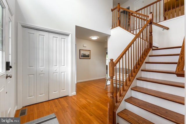 stairs featuring wood finished floors, baseboards, and a towering ceiling