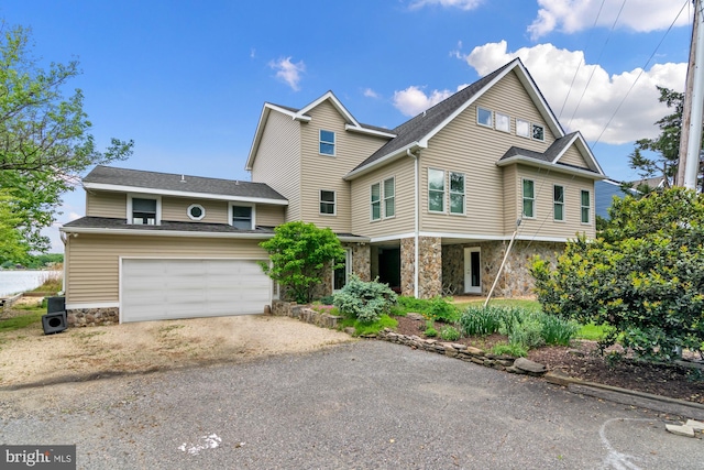 view of front of property featuring driveway, stone siding, an attached garage, and a shingled roof