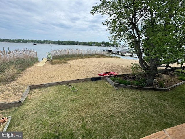 surrounding community with a water view, a dock, and a lawn