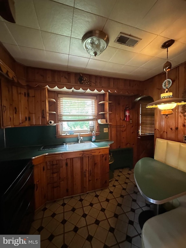 kitchen featuring open shelves, wood walls, electric range, brown cabinets, and a sink