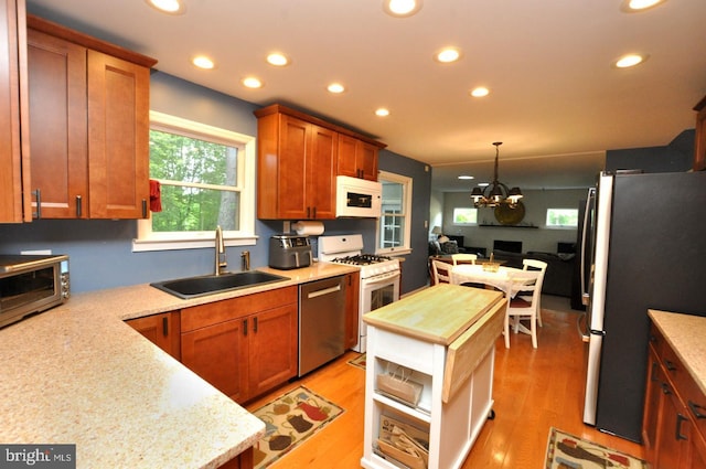 kitchen with appliances with stainless steel finishes, a sink, recessed lighting, light wood-style floors, and a chandelier