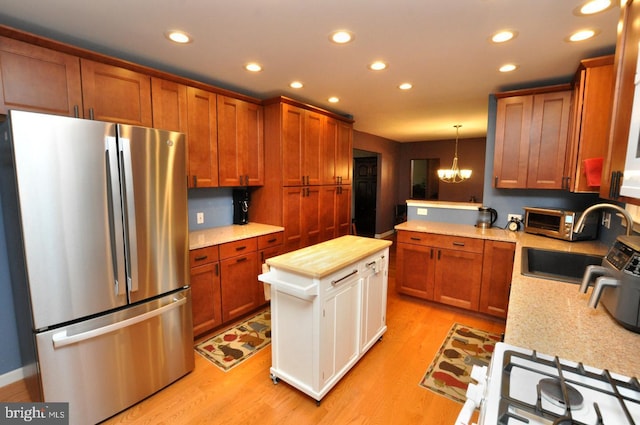 kitchen with freestanding refrigerator, a sink, recessed lighting, a chandelier, and light wood-style floors