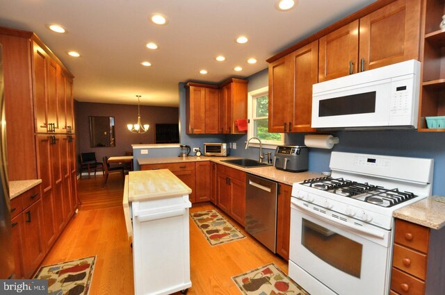 kitchen featuring white appliances, a sink, a peninsula, light wood-style flooring, and recessed lighting