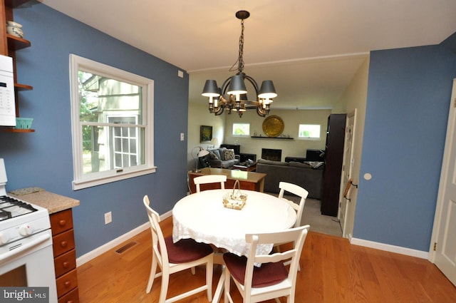 dining room with light wood finished floors, a chandelier, and plenty of natural light