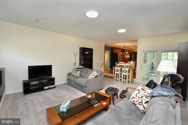 carpeted living area with a chandelier and baseboards
