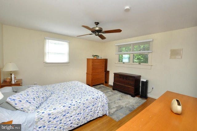 bedroom featuring wood finished floors, multiple windows, baseboards, and ceiling fan