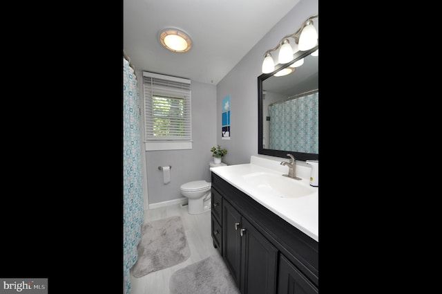 bathroom featuring vanity, toilet, baseboards, and wood finished floors