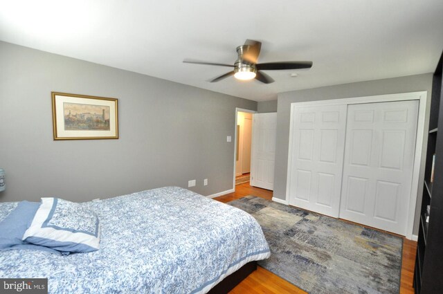 bedroom featuring a closet, a ceiling fan, wood finished floors, and baseboards
