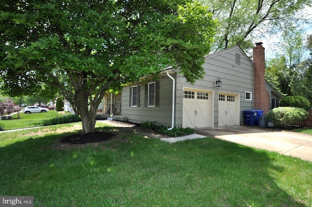 view of side of property with an attached garage, a yard, a chimney, and driveway