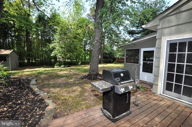 deck with grilling area, fence, an outdoor structure, and a shed
