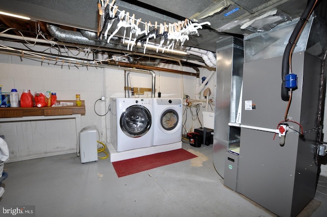 washroom with washing machine and dryer, heating unit, and concrete block wall