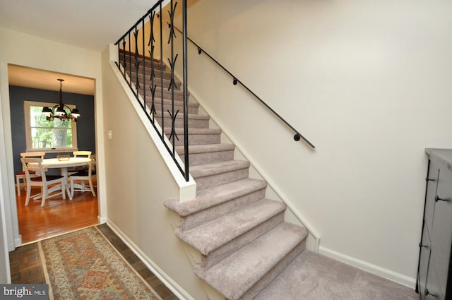 stairway with a chandelier, baseboards, and wood finished floors