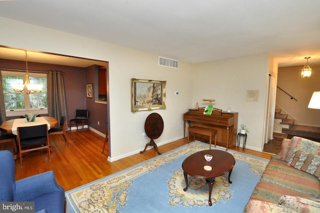 living area featuring stairs, wood finished floors, baseboards, and a chandelier