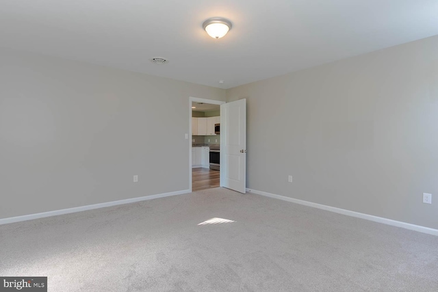 unfurnished room featuring light colored carpet and baseboards