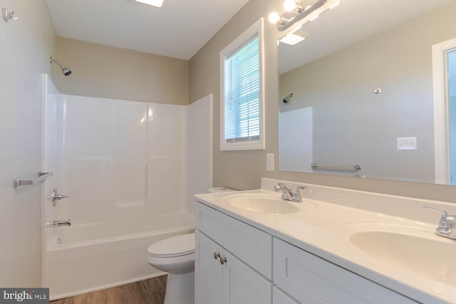 full bathroom featuring wood finished floors, shower / bathtub combination, toilet, and double vanity