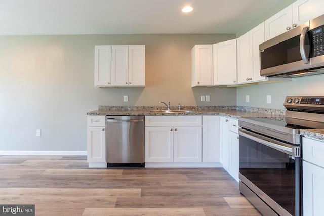 kitchen featuring stainless steel appliances, a sink, recessed lighting, white cabinetry, and stone countertops