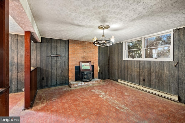 320 Dawn Ave, Woodstock, VA 22664 - unfurnished dining area featuring a baseboard radiator, wood walls, a wood stove, a chandelier, and a textured ceiling