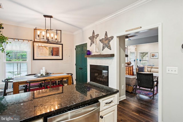 kitchen featuring ornamental molding, dark wood-style flooring, a fireplace, stainless steel dishwasher, and a chandelier