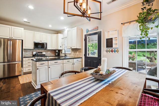 kitchen featuring appliances with stainless steel finishes, crown molding, a chandelier, dark countertops, and dark wood-style floors