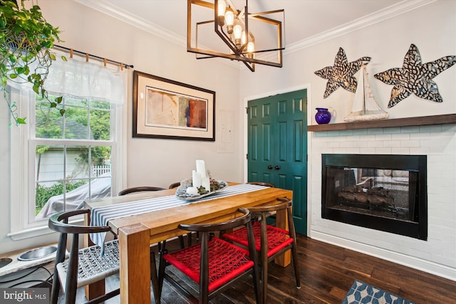 dining area with ornamental molding, dark wood-type flooring, a fireplace, and a chandelier